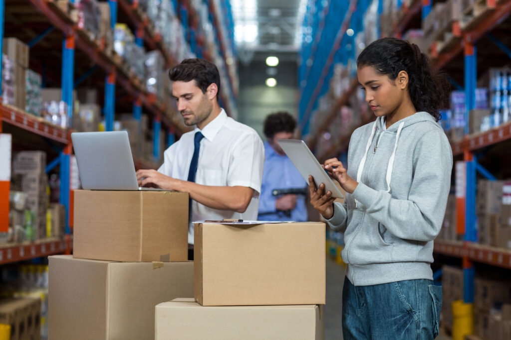 concentrate worker typing on laptop and digital tablet in warehouse