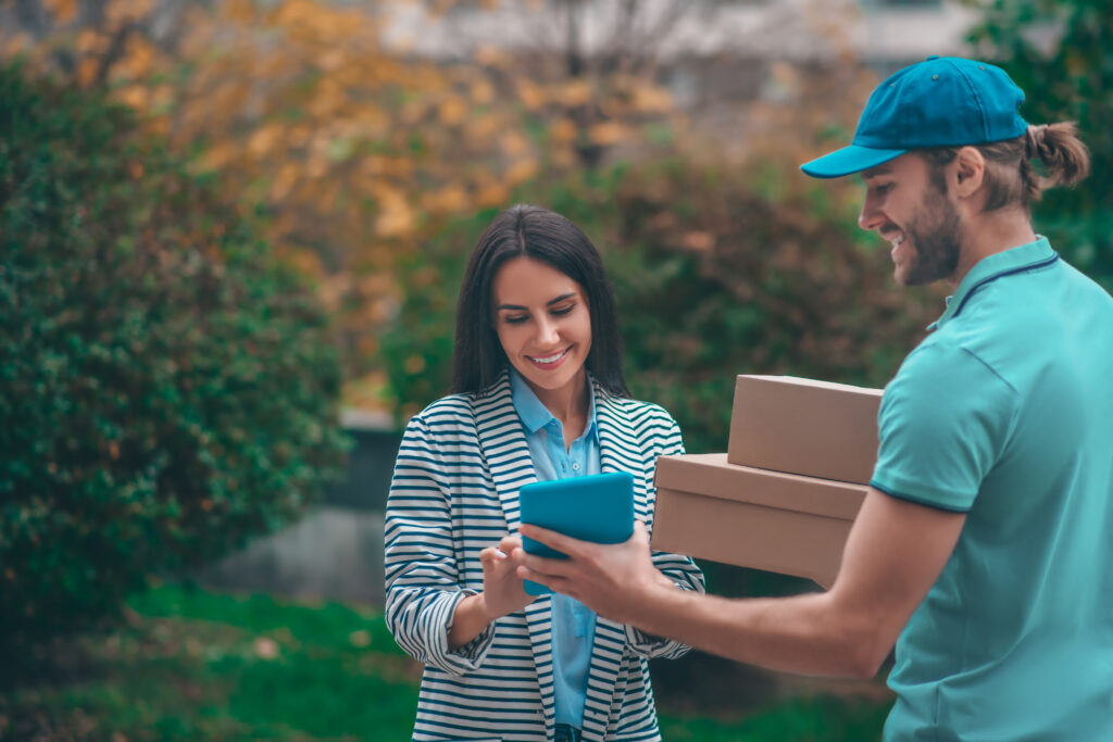 delivery man holding tablet while standing near client